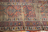 Exposed foundation among madder red and navy geometric patterns on a vintage Caucasian runner.