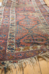 Worn field of a vintage Caucasian runner, showing tattered fringe and visible foundation.
