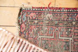 Tattered end of a vintage Karaja rug, showing visible foundation and worn geometric patterns.