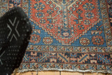 Heriz rug border detail with geometric motifs, sapphire blue, terra cotta, and worn fringe.