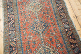 Vintage Heriz runner detail: terra cotta field, sapphire blue pomegranate, and worn hook and latch border.