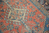 Vintage Heriz rug detail: terra cotta field, sapphire blue hook and latch motifs, showing foundation wear.
