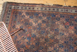 Allover geometric lattice pattern with time-softened aubergine, blue, terracotta hues on an antique Belouch rug.