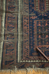Antique Belouch rug corner, featuring geometric Laleh Abbasi motifs and tattered fringe.
