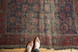Antique Belouch rug displaying allover floral lattice, indigo, dusty blush, and visible wear.
