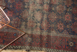 Antique Belouch rug's figural border, revealing worn indigo and wine red floral field.