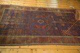 Antique Timuri Belouch rug corner, showcasing abrashed blue field, pomegranate red motifs, and an aged charcoal border.