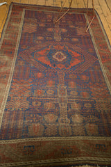 Muted pomegranate red and navy blue geometric motifs on the lower border of an antique Timuri Belouch rug.