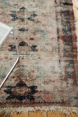 Vintage Lilihan rug corner showing exposed foundation, tattered fringe, dusty rose, and navy patterns.