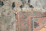 Well-worn pile exposing foundation on a vintage Lilihan rug, with tattered fringe and patterned reverse.