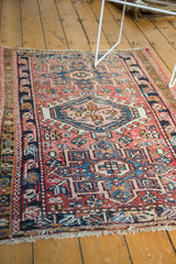 Fringed lower corner of Vintage Karaja rug, displaying blush, navy, cinnabar geometric motifs, even wear.
