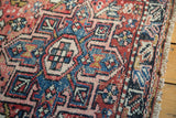 Original side cord selvage and hand-knotted geometric motifs in cinnabar red, blush, and sky blue.