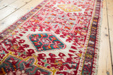 Vintage Karaja rug detail: cherry red, ivory ground, and raised teal geometric medallions.