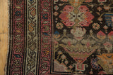 Antique Malayer rug close-up: ornate border patterns and charcoal field with rose, orange, ivory.