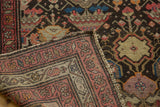 Folded corner of antique Malayer rug, revealing hand-knotted foundation, worn fringe, and mir boteh border.