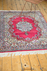 Vintage Kerman rug border with bursting florals, paisley botehs, cochineal red field, and white fringe.