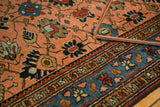Close-up of antique Lilihan rug: peach apricot field, floral vinery, contrasting blue border.