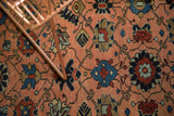 Textured detail of the antique Lilihan rug's peach field, blue and red floral vinery.