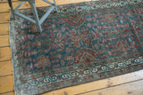 Corner of a vintage Northwest Persian runner showing teal, red floral designs, and worn pile.