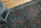 Intricate red and blue floral motifs on vintage Northwest Persian runner with visible wear.