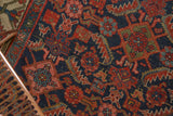 Expressive contouring of blush and saffron herati motifs on a dark indigo antique Hamadan rug.