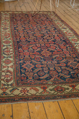 Antique Hamadan runner's ivory border features angular red and green motifs, with fringe.