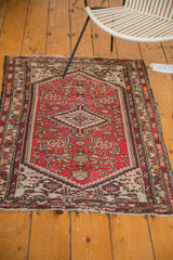 Tattered ends and border of a vintage Hamadan rug with cinnabar red and ivory patterns.