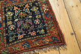 Corner view of vintage Kurdish bag face rug; geometric plants in indigo, rust, and lime green.