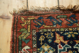 Vintage Kurdish Bag Face rug corner: dark blue field with geometric flora, rust border, and fringe.