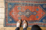 Antique Persian Malayer rug corner with aqua blue overlay and visible pile wear.