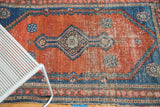 Antique Malayer rug's diamond medallion, rust field, and foundation showing through wear.