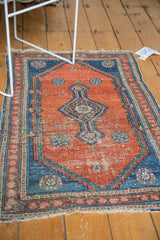 Antique Malayer rug corner, with worn pile, exposed foundation, and tattered fringe.