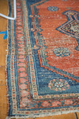 Antique Malayer rug, side detail showing faded rust field and blue border with blush motifs.