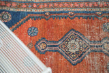 Detailed view of antique Malayer rug's diamond medallion, aqua blue motifs, and rust field with even wear.