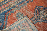 Surface wear on rust and blue antique Malayer rug, with foundation showing through and folded edge.