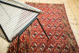 Angled view of vintage Turkmen Tent Cover rug with repeating geometric guls in brick red, navy, and ivory.
