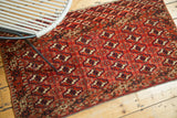 Hand knotted vintage Turkmen rug showing repeating brick red and navy geometric guls.