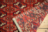 Vintage Turkmen rug with brick red geometric guls, revealing hand-knotted construction and secure side.