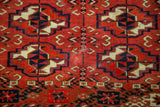 Repeating geometric guls in rich brick red, dark navy, antique ivory, on a Turkmen rug.