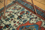 Vintage Malayer rug corner, featuring brick red, blue borders and ivory field with bloom motifs.