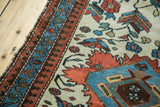 Close-up of vintage Persian Malayer rug: frayed edge, blue floral, and brick red borders.