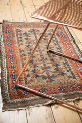 Tattered edge of a Persian Belouch rug, featuring madder root red, blue, and camel hair tree of life design.