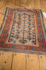 Antique Persian Belouch rug end with madder red border, geometric patterns, and tattered edge.