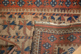 Detailed view of antique camel hair Belouch rug's tattered end and rich madder red border.