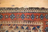 Tattered top end of antique Belouch rug, with madder red and camel hair geometric patterns.