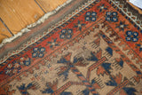Antique Belouch rug corner, natural camel hair with red border, blue patterns, and historic fringed edge.