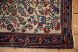 Corner detail of a fine antique Hamadan rug showing the navy border and spandrel with blush leaves.