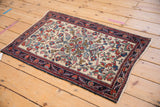 Angled view of an antique Hamadan rug with an intricate curvilinear pattern on an ivory field.