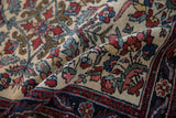 A folded corner showing the fine low pile and elaborate curvilinear motifs of an antique Hamadan rug.