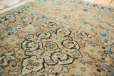 Hand-knotted vintage Sarouk rug detail showing scrolling tendrils and light blue, peach floral motifs.